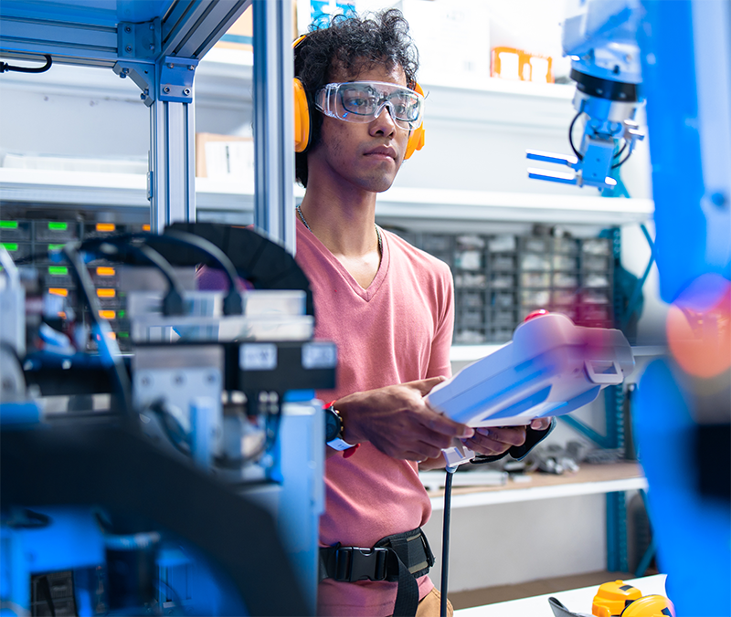 Mitarbeiter mit Gehörschutz und Tablet an einem Industrieroboter
