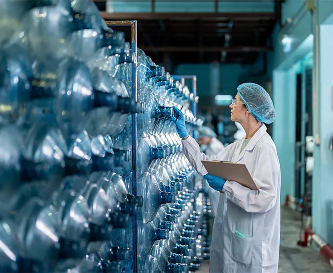 Mitarbeiterin mit Klemmbrett kontrolliert Behälter in der Produktion